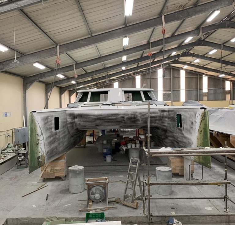 Catamaran refit and bow extension Catamaran in a workshop, with workers and materials visible inside the spacious area.